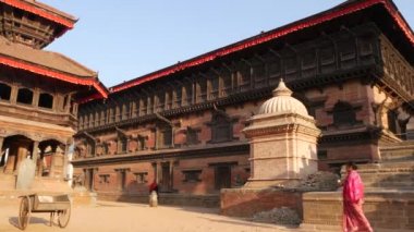 BHAKTAPUR, KATHMANDU, NEPAL - 18 Ekim 2018 Doğu antik kentinde deprem sonrası yaya trafiği. Tapınağın yakınındaki caddelerde bisiklet süren Newar 'lı bir adam.