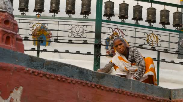 KATHMANDU, NEPAL - 8 EKİM 2018 Tapınak merdivenlerini süpüren yaşlı kadın. Renkli, geleneksel Hint kumaşlı yaşlı kadın, Swayambhunath Stupa. Kutsal Pagoda, sembol. Gün batımı ligth — Stok video