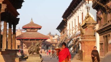 BHAKTAPUR, KATHMANDU, NEPAL - 18 Ekim 2018 Doğu antik kentinde deprem sonrası yaya trafiği. Ulusal giysili yerel newar insanları tapınağın yakınındaki sokaklara gidiyorlar.