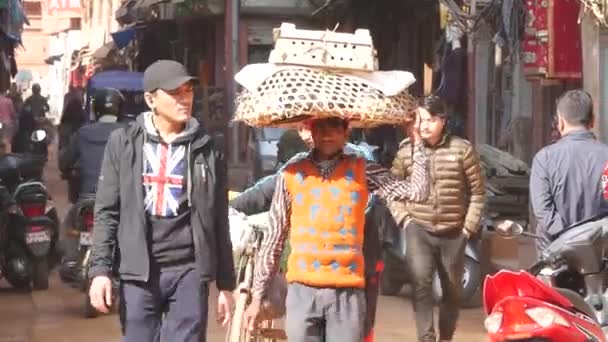 BHAKTAPUR, KATHMANDU, NEPAL - 18 October 2018人々が歩いている古代の東洋の街の通り。人の頭に鶏とバスケットを運ぶ。地震後の東洋古代都市の日常生活. — ストック動画