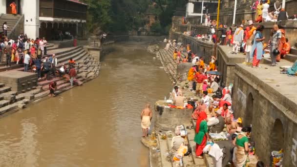 KATHMANDU, NEPAL - 8 DE OCTUBRE DE 2018: Pueblos hindúes locales, ceremonia tradicional de cremación en los ghats en llamas en la orilla del río sagrado Bagmati en el templo de Pashupatinath — Vídeos de Stock