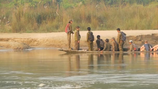 CHITWAN NATIONAL PARK, NEPAL - 10. října 2018 Turisté v kánoi plachtění na řece. Dlouhá dřevěná kánoe s turisty plovoucí na vodě řeky v zelené během safari výletu. — Stock video