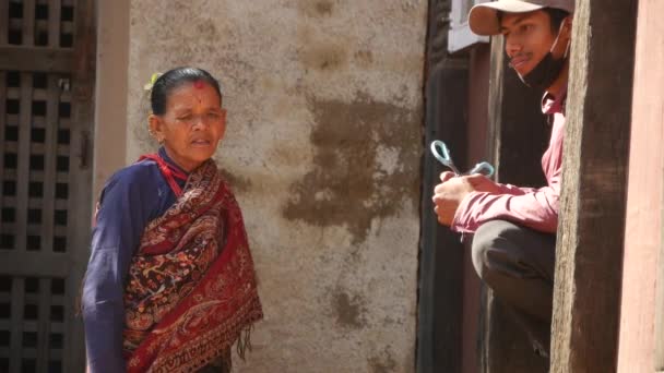 BHAKTAPUR, KATHMANDU, NEPAL - 18 жовтня 2018 року Азійський чоловік і старша жінка похилого віку в національному одязі і приємний настрій посміхаються, беруть. Громадяни повсякденного життя, зі сходу стародавнього міста після землетрусу. — стокове відео