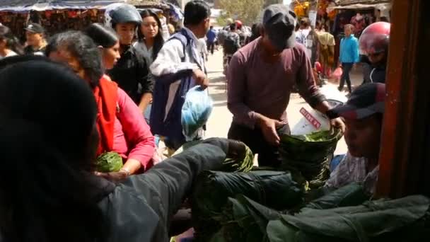 LALITPUR, NEPAL - 7 OCTUBRE 2018 Personas que rodean el puesto y la compra de pequeños platos rituales para rituales en la plaza real de Durbar, Katmandú. La vida cotidiana, ciudad antigua oriental — Vídeo de stock