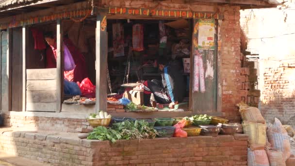BHAKTAPUR, KATHMANDU, NEPAL - 18. října 2018 Asijci prodávají zboží v národním oblečení, ranní trh s chrámem ovocné zeleniny. Denní pouliční obchod život, orientální starobylé město po zemětřesení. — Stock video