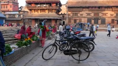 BHAKTAPUR, KATHMANDU, NEPAL - 18 Ekim 2018 Asyalılar ulusal giysiler ve sabah sebze tapınağı pazarında ürün satıyorlar. Günlük ticaret hayatı, depremden sonra antik doğu şehri..
