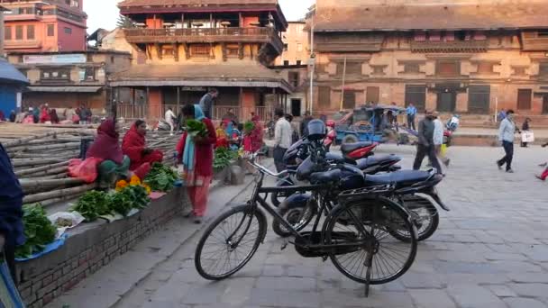 BHAKTAPUR, KATHMANDU, NEPAL - 18. října 2018 Asijci prodávají zboží v národním oblečení, ranní trh s chrámem ovocné zeleniny. Denní pouliční obchod život, orientální starobylé město po zemětřesení. — Stock video