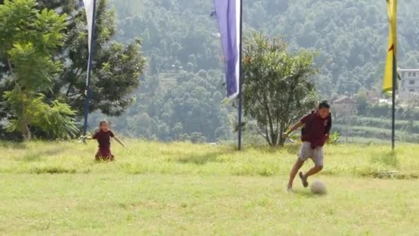BHAKTAPUR, KATHMANDU, NEPAL - 18 október 2018 Gyermek buddhista szerzetesek fociznak a zöld mezőn. Gyerekek csoportja kolostor fut zöld gyepen a templom udvarán Ázsiában. — Stock videók