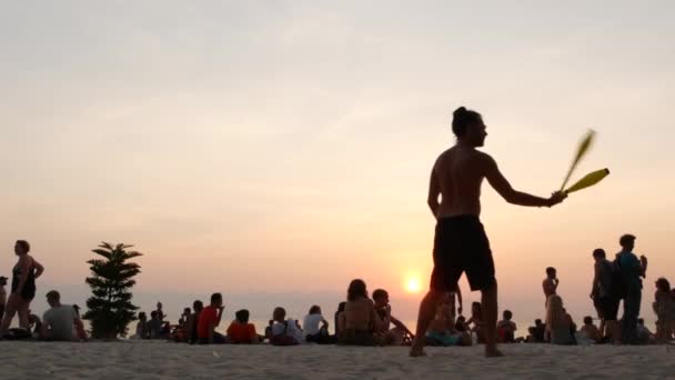 PHANGAN, THAILAND - 23 FEBRUARY 2019 Zen Beach. Mladý muž se připravuje na žonglování na pláži tropického ráje mezi velkým počtem lidí při západu slunce. Koncept svobody, společenský volný čas, cirkusová show — Stock video