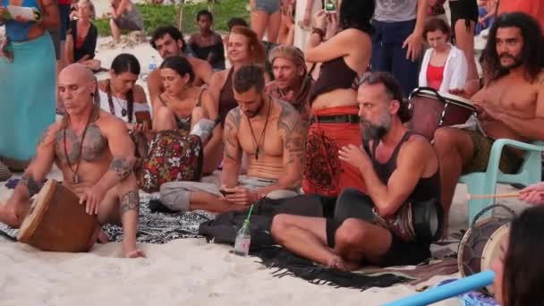 PHANGAN, TAILÂNDIA - 23 DE FEVEREIRO DE 2019 Zen Beach. Pessoas felizes tocam violão e bateria na costa do paraíso tropical de verão ao pôr do sol cercado por muitas pessoas. Engarrafamento musical, conceito de liberdade, lazer social — Vídeo de Stock