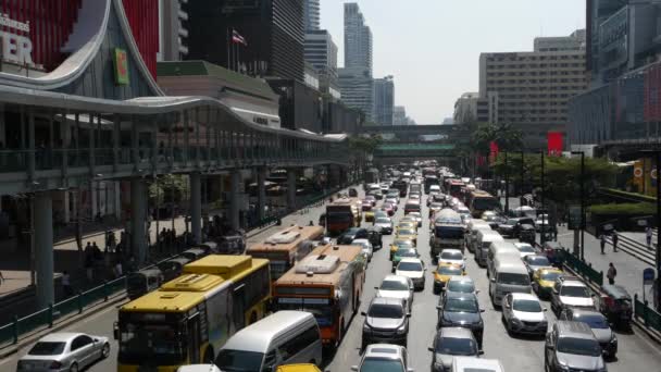 BANGKOK, Tajlandia - 18 GRUDZIEŃ, 2018: Samochody na ruchliwej ulicy miasta. Wiele nowoczesnych samochodów i autobusów jadących po ruchliwej ulicy w słoneczny dzień. zatory komunikacyjne, przeludnienie, problemy środowiskowe w miastach. — Wideo stockowe