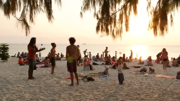 PHANGAN, THAILAND - 23 FEBRUARY 2019 Zen Beach. Mladý muž se připravuje na žonglování na pláži tropického ráje mezi velkým počtem lidí při západu slunce. Koncept svobody, společenský volný čas, cirkusová show — Stock video
