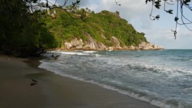 Güzel denizin yanındaki yeşil uçurum. Güneşli bir günde Tayland 'da Ko Phangan' ın engebeli yeşil uçurumunda dalgalanan görkemli mavi deniz. Egzotik Tropik Cennet Sahili.