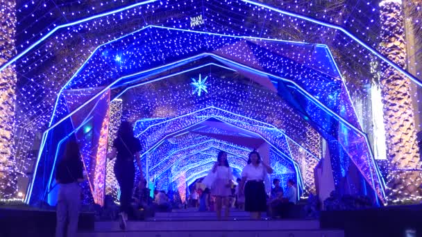 BANGKOK, THAILAND - 18 DECEMBER, 2018: Siam Paragon. Люди ходять у освітленому коридорі. Азійці в повсякденному одязі ходять по кроках яскраво освітленою аркою на вулиці.. — стокове відео