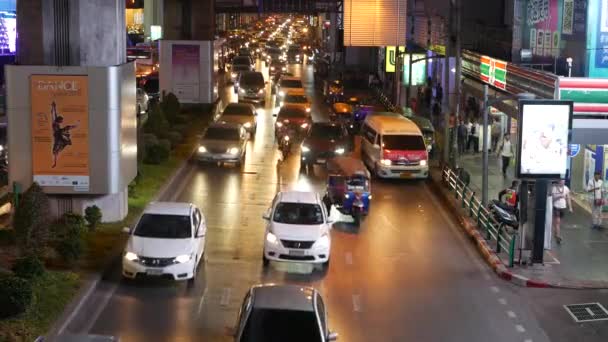 BANGKOK, THAILANDIA - 18 DICEMBRE 2018: Auto in un ingorgo sulla strada della città asiatica sovrappopolata della capitale tailandese di notte. luci elettriche gialle e rosse, tuk tuk, bus — Video Stock