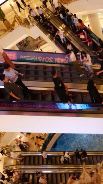 BANGKOK, TAILANDIA - 18 DE DICIEMBRE DE 2018: Siam Paragon centro comercial asiático interior. Multitud de personas en las escaleras mecánicas del centro comercial. La gente se apresura a ir de compras en plaza moderna. Consumo de bienes — Vídeo de stock