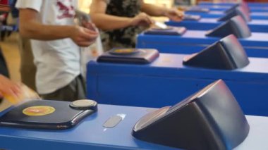 Tren istasyonuna giriş kartı kullanan isimsiz insanlar. Kırpılan insanlar, Skytrain istasyonuna girerken turnikelerde plastik araba kullanıyorlar..