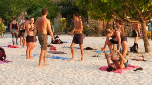 PHANGAN, TAILÂNDIA - 23 DE FEVEREIRO DE 2019 Zen Beach. Os jovens fazem acro ioga na areia. exercícios de energia ao ar livre. lazer social coletivo. pôr-do-sol de verão no paraíso trópico. Conceito de liberdade. — Vídeo de Stock