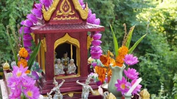 Wooden miniature guardian spirit house. Small buddhist temple shrine, colorful flower garlands. San phra phum erected to bring fortune. Traditional respect animistic rituals, pray ceremonies — Stock Video