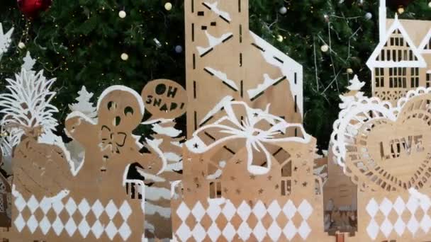 Decoraciones de madera contrachapada para árbol de Navidad. Varios ornamentos de madera contrachapada colocados cerca del árbol de coníferas verdes durante la celebración de Navidad — Vídeo de stock