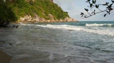 Güzel denizin yanındaki yeşil uçurum. Güneşli bir günde Tayland 'da Ko Phangan' ın engebeli yeşil uçurumunda dalgalanan görkemli mavi deniz. Egzotik Tropik Cennet Sahili.