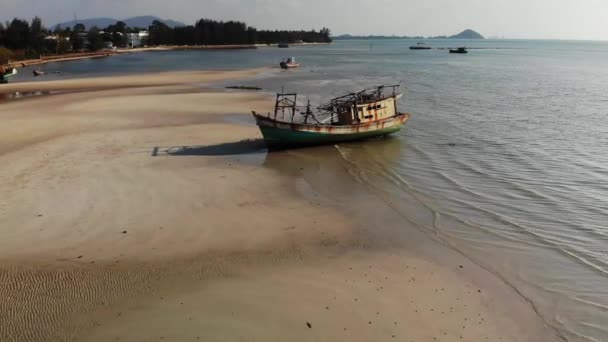 Su kenarında kum sahilinde balıkçı gemisi. Güneşli bir günde denize yakın kum kıyısında eski ıssız paslı balıkçı teknesi, koh Samui Hava drone görünümü. — Stok video