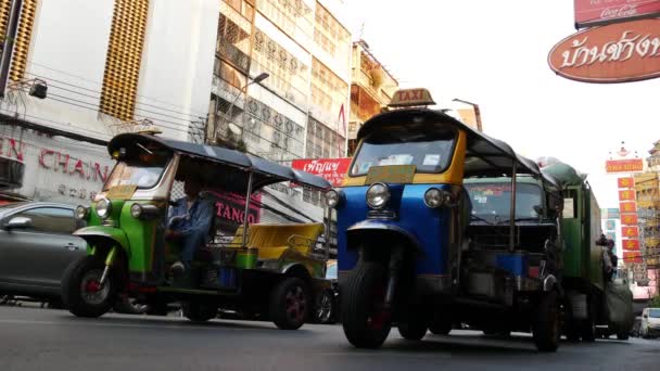 BANGKOK, THAILAND - 18 Mart 2019: Tuk tuks Asya şehrinde. Bangkok 'ta Çin Mahallesi' nin işlek caddesinde asfalt yolda giden renkli otomobil tribünleri.. — Stok video