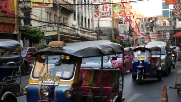 BANGKOK, THAILAND - 18 Mart 2019: Tuk tuks Asya şehrinde. Bangkok 'ta Çin Mahallesi' nin işlek caddesinde asfalt yolda giden renkli otomobil tribünleri.. — Stok video