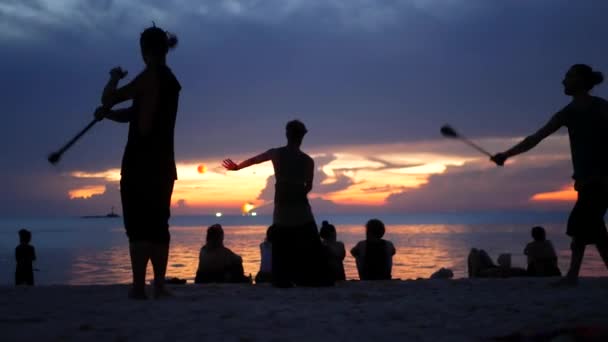 PHANGAN, THAILAND - 23. März 2019 Zen Beach. Silhouetten von Performern am Strand während des Sonnenuntergangs. Silhouetten von jungen anonymen Entertainern, die am Sandstrand vor ruhiger See und Sonnenuntergang proben. — Stockvideo