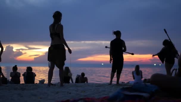 PHANGAN, TILLAND - 23 Mars 2019 Zen Beach. Silhuetter av artister på stranden under solnedgången. Silhuetter av unga anonyma underhållare repeterar på sandstrand mot lugnt hav och solnedgång himmel. — Stockvideo