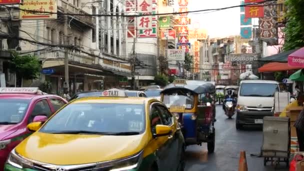 BANGKOK, Tajlandia - 18 marca 2019: Tuk tuks na ulicy azjatyckiego miasta. Kolorowe auto riksze jazdy na asfaltowej drodze na ruchliwej ulicy Chinatown w Bangkoku. — Wideo stockowe