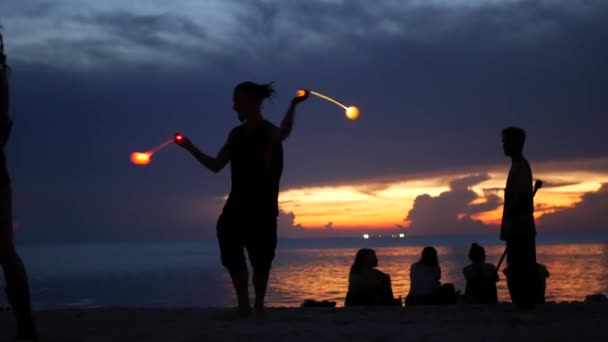 PHANGAN, THAILAND - 23. März 2019 Zen Beach. Silhouetten von Performern am Strand während des Sonnenuntergangs. Silhouetten von jungen anonymen Entertainern, die am Sandstrand vor ruhiger See und Sonnenuntergang proben. — Stockvideo