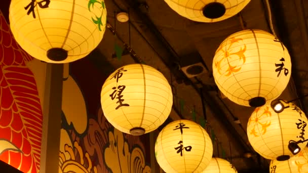 Papírové lucerny svítí na ulici. Krásné papírové lucerny svítily a visely v úzkém průchodu po japonské ulici. Orientální výzdoba. — Stock video