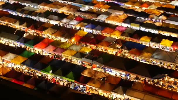 Tenda pasar bercahaya di malam hari. Pemandangan paling atas dari tenda-tenda terang berwarna-warni dari Pasar Malam Kereta Api Ratchada Fai di jalan wisata Bangkok. Atraksi populer, makanan jalanan dan berbelanja — Stok Video