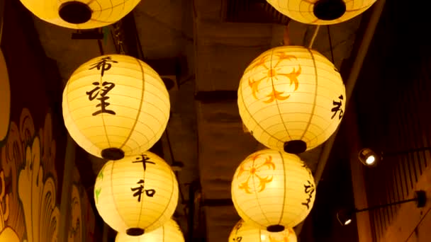 纸灯笼照耀在大街上。美丽的纸灯笼在日本街上的狭窄通道上悬挂时闪闪发光。东方装饰. — 图库视频影像