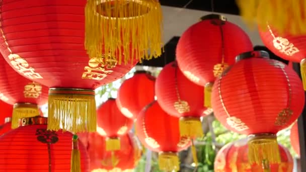 Linternas de papel en un edificio de mala calidad. Faroles de papel rojo colgando en el techo del edificio del templo de hormigón envejecido en el día soleado en el país oriental. decoración tradicional — Vídeos de Stock