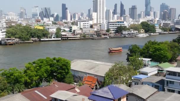Distrito financeiro perto do rio calmo. Vista de arranha-céus localizados na costa do tranquilo rio Chao Praya, no centro do distrito de Bangkok. Panorama da vida da cidade grande. Barcos na água em Krungthep. — Vídeo de Stock
