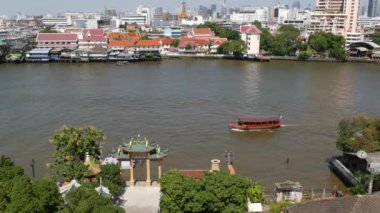 Krungthep şehrinde nehirde yüzen doğu teknesi. Çin Mahallesi yakınlarındaki Bangkok 'ta güneşli bir günde Chao Praya nehrinde yüzen modern nakliye gemisi. Panorama