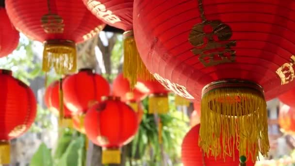 Paper lanterns on shabby building. Red paper lanterns hanging on ceiling of weathered concrete temple building on sunny day in oriental country. traditional decoration — Stock Video