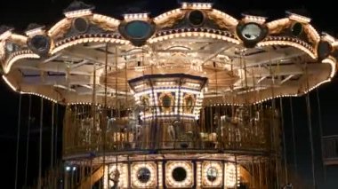 Işıklı neşeli parkta yuvarlak gidin. Geceleri harika bir eğlence parkında dönen parlak ışıklı kavşak