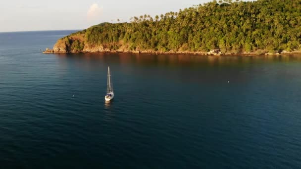 Barco perto da costa tropical. Incrível drone vista do moderno iate de luxo branco navegando em águas calmas do mar perto da costa da ilha tropical . — Vídeo de Stock