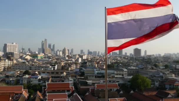 Paysage urbain de la ville orientale moderne. Vue sur les maisons toits dans les rues de Bangkok majestueux de Golden Mount Temple pendant l'heure du coucher du soleil. Grand drapeau et symbole de la Thaïlande balançant sur le vent — Video