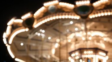 Aydınlanmış, bulanık, neşeli parkta dolaş. Aydınlatılmış döner kavşak gece vakti harika bir lunaparkta dönüyor.