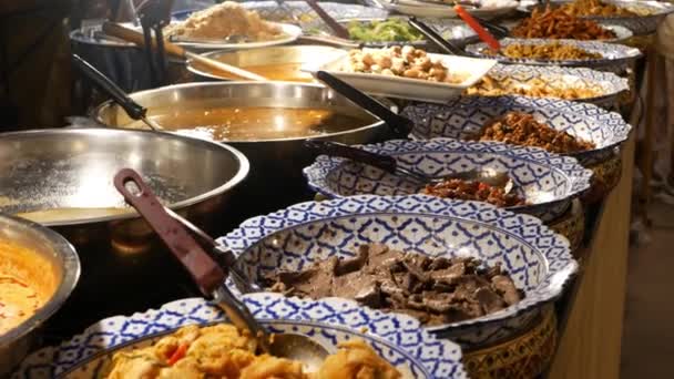 Cuencos con varios platos asiáticos en el puesto. Cuencos de surtidos platos tradicionales tailandeses colocados en el puesto de comedor de la calle por la noche. Mercado nocturno oriental patio de comidas. — Vídeo de stock