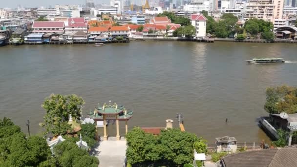 Krungthep şehrinde nehirde yüzen doğu teknesi. Çin Mahallesi yakınlarındaki Bangkok 'ta güneşli bir günde Chao Praya nehrinde yüzen modern nakliye gemisi. Panorama — Stok video