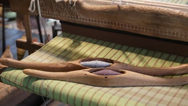 Threads on old loom. Wooden shuttles with natural threads placed on weaved fabric aged loom. — Stock Video