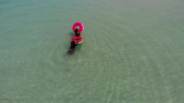 KOH SAMUI, TAILANDIA - 8 DE MAYO DE 2019. Playa Chaweng. Niños nadando en tubos en el mar. Dos niños étnicos que se divierten mientras nadan en agua de mar en tubos inflables en el resort . — Vídeo de stock