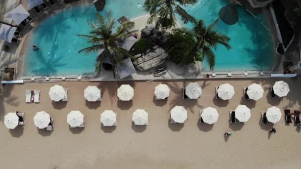 海滩上的日光浴床。在荒凉的海滩上,许多配对的太阳椅与伞与干净的沙滩的鸟瞰图. — 图库视频影像