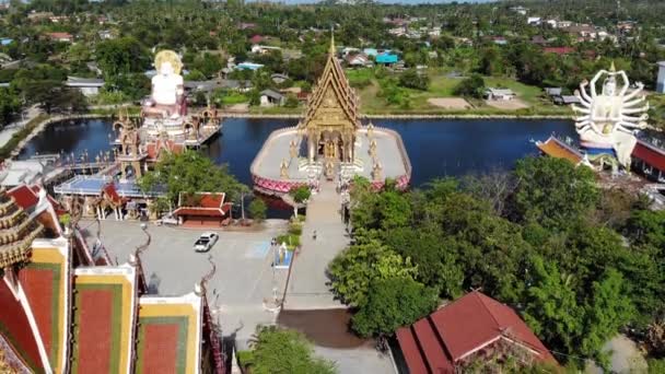 Buddhistiskt tempel nära sjön. Drone topputsikt över tak och statyer av underbara buddhistiska tempel ligger nära sjön på soliga dagen på Ko Samui. Wat Plai Laem med leende Buddha och Guan Yin — Stockvideo