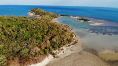 Okyanustaki küçük ada ve mercan resifi. Tropikal doğada güneşli bir günde sakin denizde yeşil ıssız bir ada ve inanılmaz mercan resifinin insansız hava aracı görüntüsü. Koh Samui, Tayland.